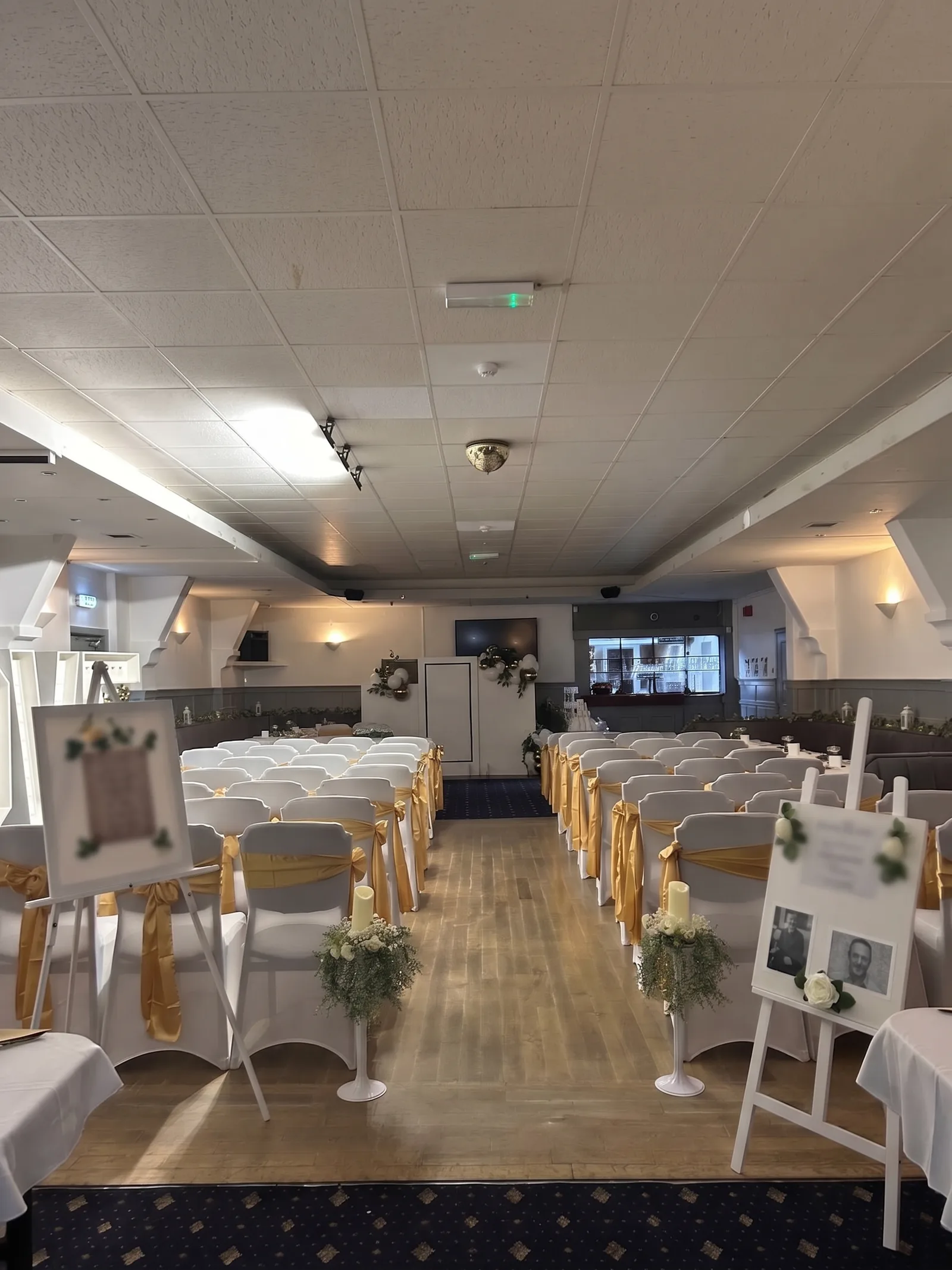 The club set up for a ceremony, with rows of white chairs and gold bows