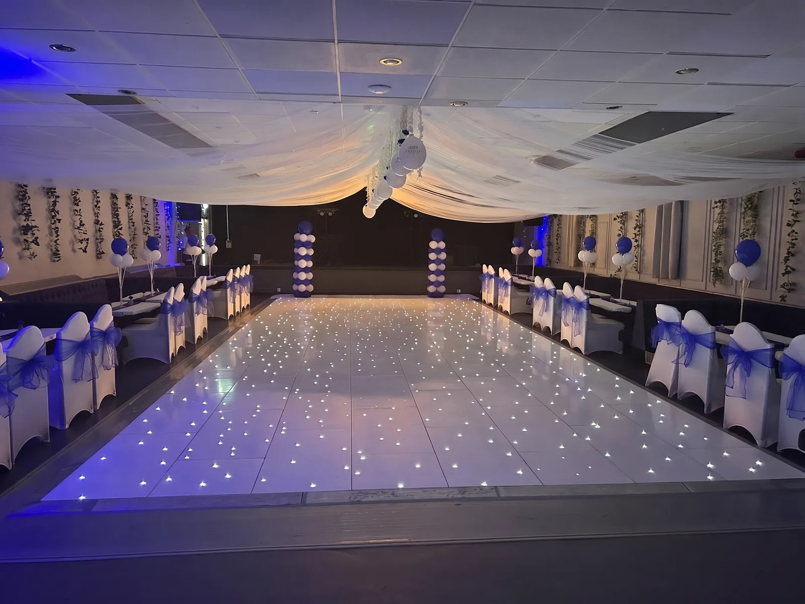 The function hall decorated in blue and white, with a sparkling dance floor