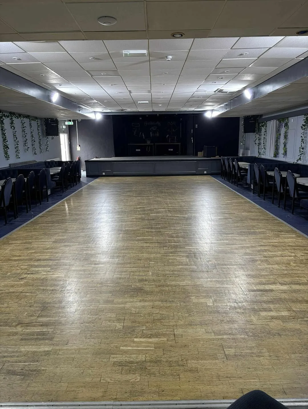The hall with an open wooden dance floor, seating and a stage